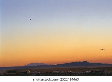 Training aircraft flying over the Prescott Love Field Airport at sunset with the San Francisco mountain Peaks of Flagstaff Arizona on the horizon - Powered by Shutterstock