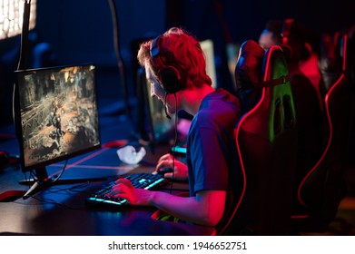 Training Bootcamp For Professional Esports Players. Young Cyber-athletes Play An Online Shooter Game. Glowing Keyboard, Neon Light.