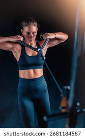 Training on a back cable machine in the gym, a woman enhances shoulder strength and coordination. This versatile exercise promotes long term health