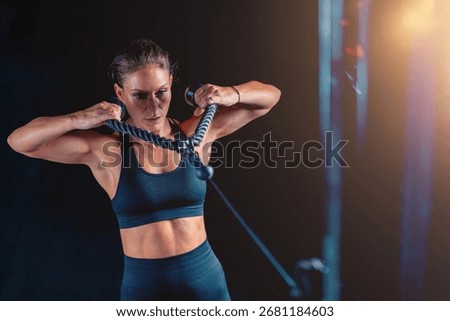 Training on a back cable machine in the gym, a woman enhances shoulder strength and coordination. This versatile exercise promotes long-term health and boosts confidence with targeted resistance.