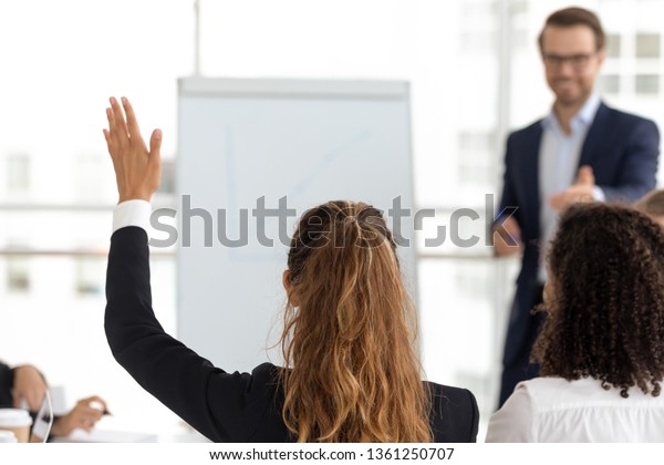 Training participant raise hand ask question get\
engaged involved in voting initiative at employees team workshop,\
corporate knowledge, business education, volunteer participation\
concept, rear view