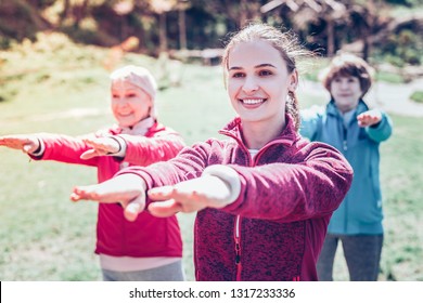 Training retired women. Young professional and experienced dark-eyed fitness trainer training retired women - Shutterstock ID 1317233336