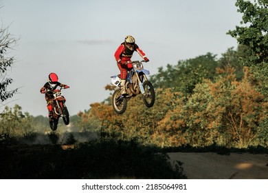 Training with trainer. Live shot of junior sportsman, motorcyclist riding on motorbike at hot summer day, outdoors. Motocross sport, competition, male hobby, energy and ad