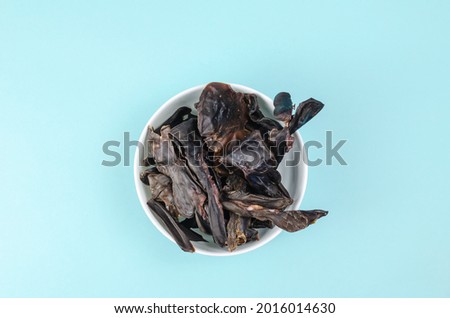 Training treats for pets on blue background. Natural Air Dried dog treats in a white ceramic bowl. Yummy Thin slices of dehydrated beef kidneys. Top view