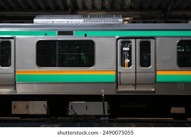 Trains, Japanese local train exterior with green and orange stripes on platform of railway station in Japan. Passenger locomotive at Atami railway station platform in Japan outdoor at daytime. - Powered by Shutterstock