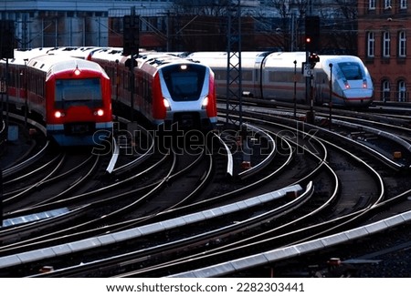 Trains on curved tracks of a main railway line in Hamburg Germany in morning dawn blue hour twilight. Different types of multiple units at rushhour approaching main station with glistening rails.