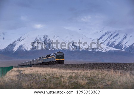 Trains on the Qinghai-Tibet Railway line under the Kunlun Yuzhufeng Snow-mountain.