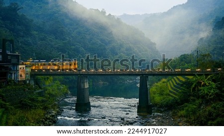 Trains pass over the bridge. The station next to a stream in a foggy valley. Sandiaoling, Ruifang District, New Taipei City, Taiwan