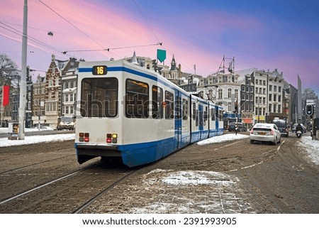 Tram driving in snowy Amsterdam in the Netherlands at sunset