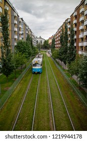 Tram Line Two In Göteborg, Sweden, Photographed From A Bridge When Its Leaving Tram Stop Seminariegatan In Between Yellow Brick Buildings, Driving On Green Grass