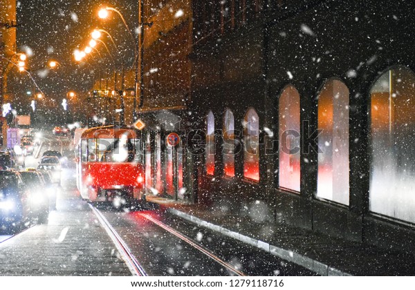 Tram in night street and\
snow storm