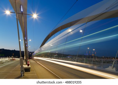 Tram speeding over a bridge in Lyon at dusk.