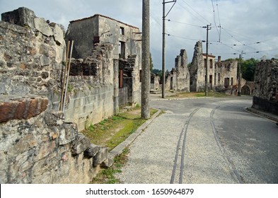 Tramlines Leading The Way Through Ruined Buildings In Oradour-sur-Glane, Left As A War Memorial In France. Empty Street Showing  The Destruction Of A Village In War Torn Europe. Empty Village. WW2 