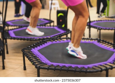 Trampoline fitness jumping training, group of young fit women in sportswear jump on trampolines, girls training with coach instructor, exercising on rebounder at the gym, mini trampoline workout - Powered by Shutterstock