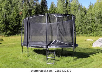 Trampoline with safety net in the garden - Shutterstock ID 2283432679