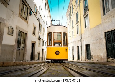 Trams In Lisbon. Famous Retro Yellow Funicular Tram On Narrow Streets Of Lisbon. Tourist Sightseeing Or Tourist Attraction In Lisbon, Portugal