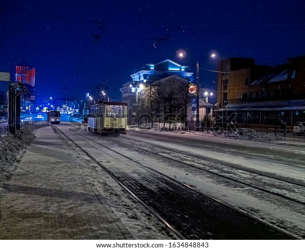 trams travel along the winter night street of\
Kirov during a snowfall in\
Chelyabinsk