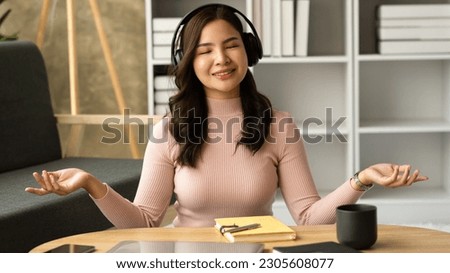 Tranquil asian woman listening favorite song in headphones, enjoying peaceful weekend time at home