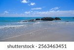 A Tranquil Beach Scene With Clean White Sandy Beaches, With Rugged Rocks Jutting Out Of The Shallow Water