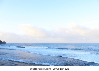 A tranquil beach at sunrise with calm waves and soft morning light. Ideal for relaxation and vacation concepts. High-res image capturing the peaceful essence of morning by the sea.