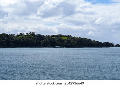 A tranquil coastal scene featuring a small fishing boat near a lush green island, surrounded by calm waters and a picturesque cloudy sky, perfect for nature lovers. - Powered by Shutterstock