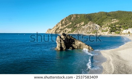 A tranquil day at Cinque Terre features gentle waves on vibrant blue waters and soft sandy beaches, all beneath a serene, clear sky. Monterosso Italy