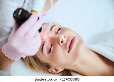 Tranquil female patient lying with closed eyes during the laser treatment in a beauty clinic - Shutterstock ID 1870335898