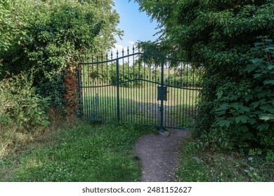 Tranquil garden path through lush greenery ends with an ornate garden gate leading to a sunlit mountain. - Powered by Shutterstock