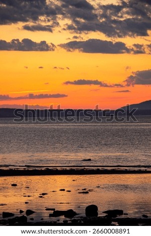 A tranquil horizontal landscape captures the dramatic colors of a sunset over the beach at Port Seton, Scotland