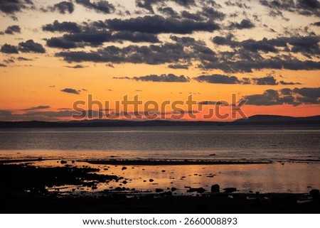 A tranquil horizontal landscape captures the dramatic colors of a sunset over the beach at Port Seton, Scotland