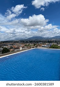 A tranquil infinity pool reflecting the bright blue sky and soft clouds, offering a peaceful and luxurious escape