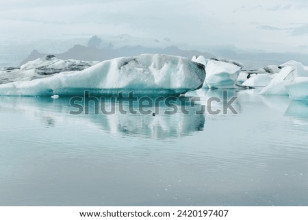 Tranquil isolated landmark blue Iceland glacier lake Jokulsarlon with floating icebergs and snowy mountain background textured environment 