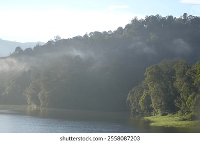 A tranquil lake mirroring the misty mountains under the morning light. The scene evokes a sense of peace and serenity. - Powered by Shutterstock