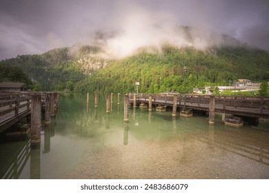 Tranquil lakeside dock with misty mountains, greenery, and peaceful surroundings, creating a serene and beautiful scene. Berchtesgaden National Park, Alps Germany - Powered by Shutterstock