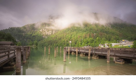 Tranquil lakeside dock with misty mountains, greenery, and peaceful surroundings, creating a serene and beautiful scene. Berchtesgaden National Park, Alps Germany - Powered by Shutterstock
