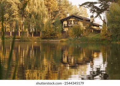 A tranquil lakeside retreat surrounded by vibrant autumn foliage reflects beautifully on the calm water. - Powered by Shutterstock