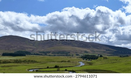 A tranquil landscape featuring a winding river through lush green meadows and rolling hills.