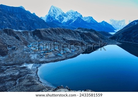 Tranquil morning scene of Cholatse,Taboche and Kangtega rising over mirror like Gokyo Lake and Gokyo village on the ascent of Gokyo Ri in the Khumbu region,Nepal