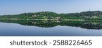 A tranquil mountain lake surrounded by tall trees and lush greenery in Ville saguenay