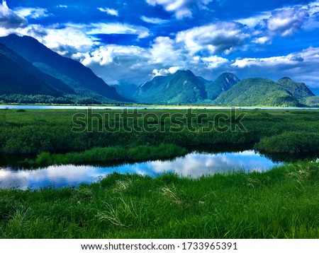 Tranquil mountain valley with blue skies, clouds reflected in water surface of lake. Pacific Northwest, British Columbia Canada. Chilliwack