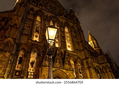 Tranquil, night scene of a vintage wrought iron street lantern seen lit against a majestic cathedral in York, England. - Powered by Shutterstock