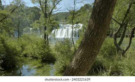 A tranquil oasis nestled within the vibrant greenery of a state park, as a cascading waterfall glistens in the sunlight, inviting us to immerse ourselves in the peaceful embrace of nature's bounty - Powered by Shutterstock