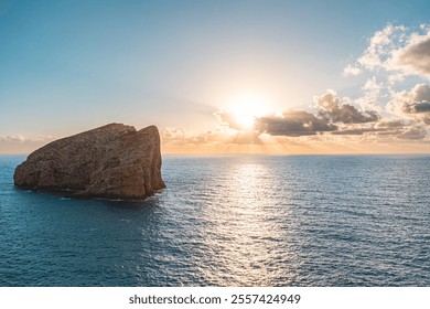 Tranquil ocean scene at sunset featuring a solitary rocky island. The warm sunlight filters through clouds, casting serene reflections on the water, under a clear blue sky. Ideal for relaxation themes - Powered by Shutterstock