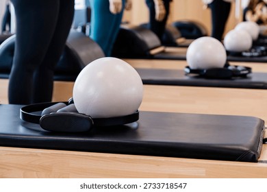 A tranquil Pilates studio interior featuring neatly arranged reformers, soft exercise balls, and supportive straps. Warm natural light fills the space, highlighting the clean, organized layout and inviting atmosphere. This serene setting embodies wellness, balance, and a commitment to holistic fitness, making it ideal for health, exercise, and lifestyle concepts.