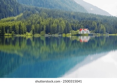 Tranquil Reflections of a Lakeside House Surrounded by Lush Forests in Late Afternoon - Powered by Shutterstock