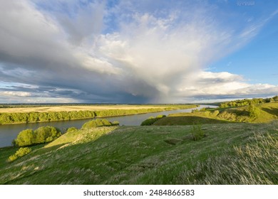  A tranquil river landscape under a dramatic sky with a rainbow, showcasing a meandering river, lush greenery, and a mix of sunlight and shadows. - Powered by Shutterstock