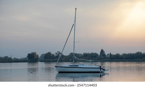 A tranquil sailboat floats on a serene lake at sunset, embodying relaxation and escape from daily stress - Powered by Shutterstock