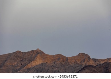 Tranquil scene of a barren desert mountain peak under a soft, cloudy sky, Ranikot, Sindh, Pakistan - Powered by Shutterstock