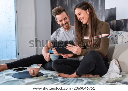 Tranquil scene of a couple using tablet sitting on the bed in the morning