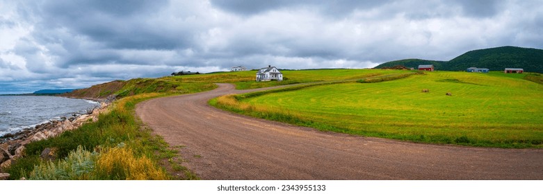 Tranquil seascape with coastal green hills, curving dirt road, and view of Gulf of St Lawrence in Saint Joseph du Moine, Nova Scotia, Canada - Powered by Shutterstock